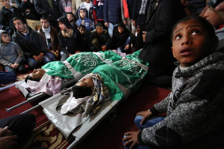 Relatives mourn over the bodies of two Palestinian teenagers, who were killed following Israeli air strikes, during their funeral