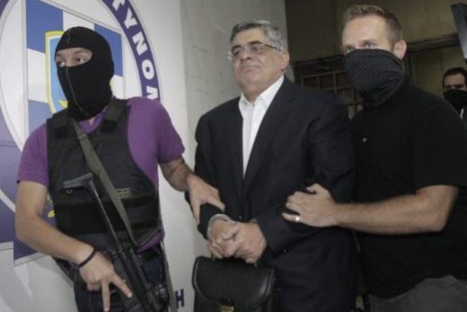 Far-right Golden Dawn party leader Mihaloliakos is escorted by anti-terrorism police officers as he leaves the Greek police headquarters in Athens