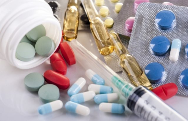 Syringe, blisters with colorful pills and capsules